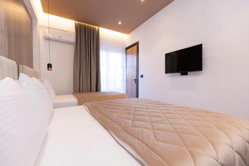a bedroom with a large bed with a television on the wall at Hotel Joni Premium in Ksamil