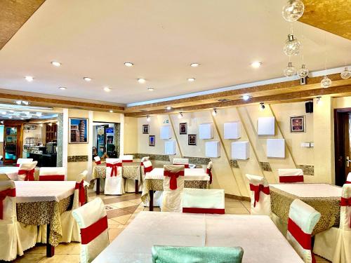 un restaurante con mesas blancas y sillas rojas en Kharaa Hotel & Restaurant, en Ulán Bator