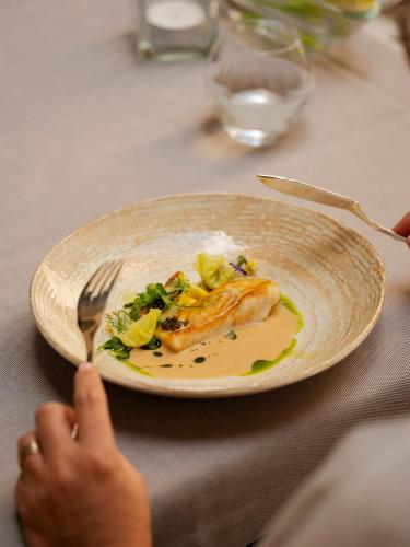 a plate of food on a table with a person holding a fork at Hotel Copernicus in Kraków