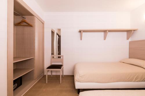 ein kleines Schlafzimmer mit einem Bett und einem Stuhl in der Unterkunft Apartamentos Malacosta - MC Apartamentos Ibiza in Ibiza-Stadt