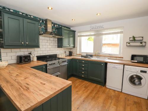 a kitchen with green cabinets and a wooden counter top at 32 Friar Row in Wigton