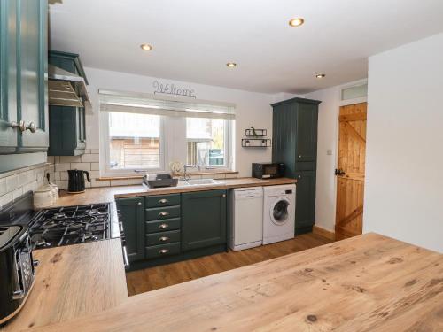 a kitchen with green cabinets and a washer and dryer at 32 Friar Row in Wigton