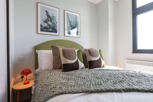 a bedroom with a bed with a green headboard at Palm Tree House - Sahara in Orpington
