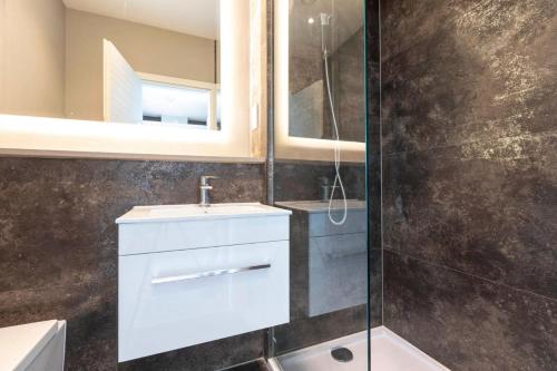 a bathroom with a white sink and a shower at Palm Tree House - Sahara in Orpington