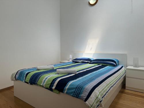 ein weißes Schlafzimmer mit einem Bett mit gestreifter Decke in der Unterkunft Apartment Sea Shell in Medulin