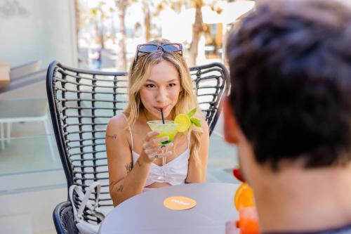 a woman sitting at a table with a drink at Cabot Playa Grande - Adults Only in Playa de Palma