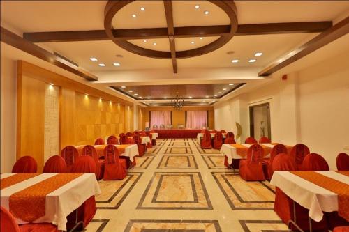 un salón de banquetes con mesas y sillas y una lámpara de araña en Hotel The Amaris, en Rishīkesh