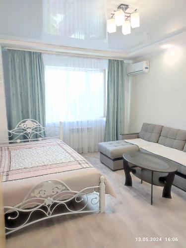 um quarto com uma cama, um sofá e uma mesa em Современная квартира с видом на горы em Almaty