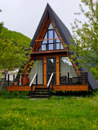 une petite maison avec un toit noir sur un champ verdoyant dans l'établissement B&B Cottage in Mestia, à Mestia