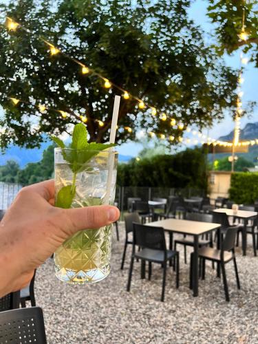 a hand holding a glass with a green drink at Glamping Camping Rivabella in Lecco