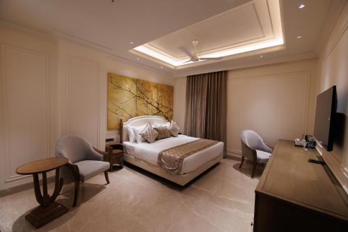 1 dormitorio con 1 cama, sillas y TV en Hotel Maharaja Palazzo en Ludhiana