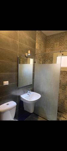 Un baño con lavabo, inodoro y espejo. en Your room, en El Cairo