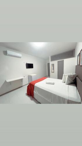 two white beds in a room with a tv at Pituba Suítes in Salvador