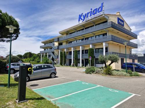 a building with a parking lot in front of it at Kyriad Carcassonne - Aéroport in Carcassonne
