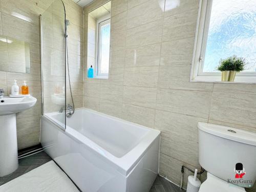 a bathroom with a tub and a toilet and a sink at KozyGuru Spacious 3 BR 8ppl Hse 50% off Long stay in Manchester