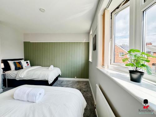 two beds in a small room with a window at KozyGuru Spacious 3 BR 8ppl Hse 50% off Long stay in Manchester