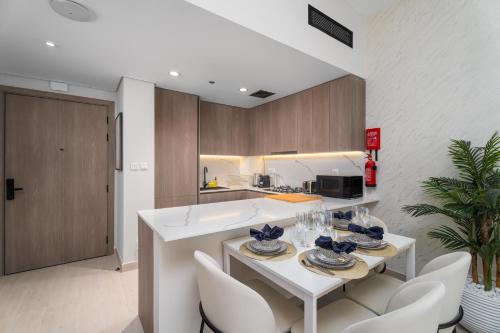 a kitchen with a white table and white chairs at Nasma Luxury Stays - Laya Heights in Dubai