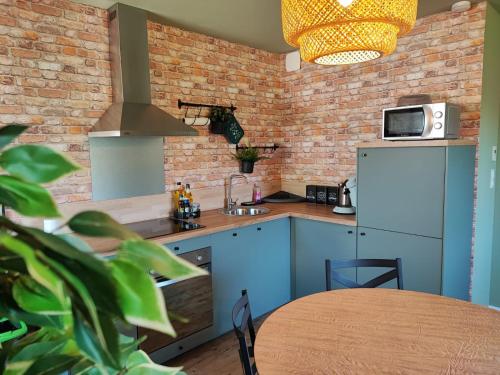 une cuisine avec des placards bleus et un mur en briques dans l'établissement Le cocon de Jeannette, à Bergheim