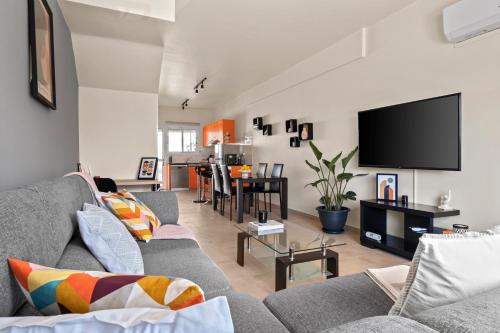a living room with a couch and a flat screen tv at Orange Bliss Townhouse by Nomads in Peyia