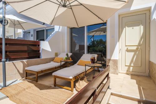 a patio with two chairs and an umbrella at Orange Bliss Townhouse by Nomads in Peyia