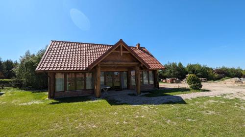 a small cabin with a roof on a grass field at Dom pod Modrzewiem in Świątki