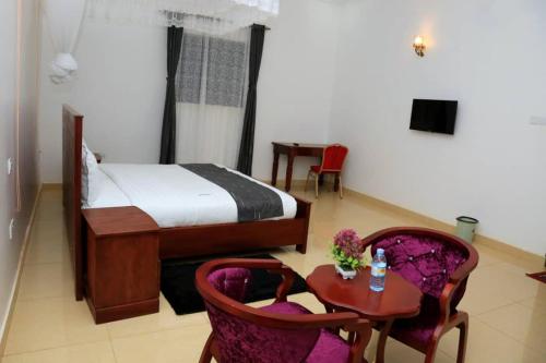 a bedroom with a bed and a table and chairs at Fort Breeze Hotel in Fort Portal