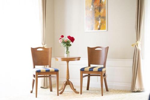 twee stoelen en een tafel met een vaas met bloemen bij Scuol Palace Bed & Breakfast in Scuol