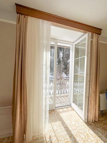 a room with a large sliding glass door to a balcony at Scuol Palace - Culture, Nature & Health in Scuol