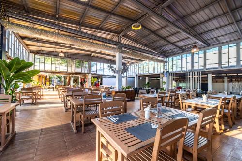 巴東海灘的住宿－Karon Island Boat Boutique Hotel，餐厅设有木桌、椅子和窗户。
