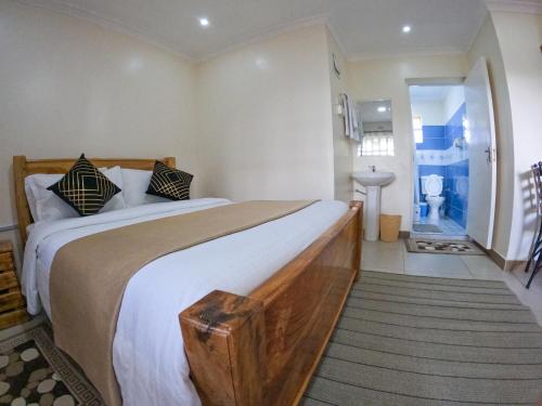 een slaapkamer met een groot bed en een badkamer bij Mayas Suites in Nyeri