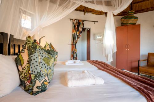 ein Schlafzimmer mit einem Bett mit weißer Bettwäsche und einem Stuhl in der Unterkunft Africa on Foot in Klaserie Private Nature Reserve