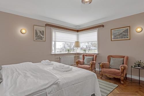 um quarto branco com uma cama e 2 cadeiras em Audur Guesthouse em Reykjavík