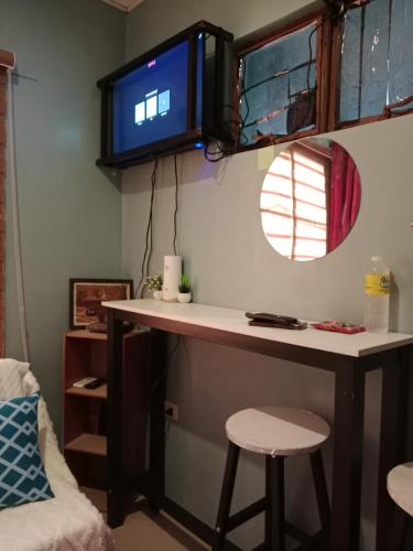 escritorio en una habitación con TV en la pared en Dencios Transient en Cabuyao