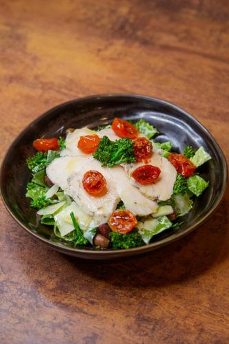 a bowl of salad with chicken and vegetables on a table at Boutique Hotel Piazza Grande in Locarno