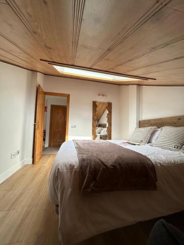 a bedroom with a large bed with a wooden ceiling at Villa los corzos in Oviedo