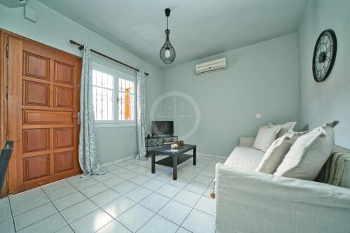 a living room with a couch and a clock on the wall at Ira Apartment in Ermioni