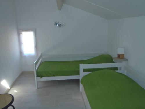 une chambre avec deux lits avec des draps verts dans l'établissement VILLA 3 PCES MEZ 48m2 + TERRASSE 7m2 REF 4034, à Le Castellas