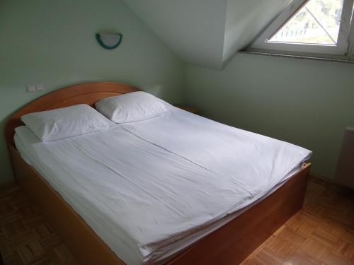 um quarto com uma cama com lençóis brancos e uma janela em Gostišče Hochkraut em Celje