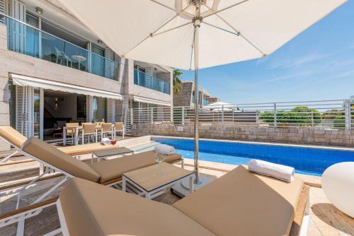 an outdoor patio with an umbrella and a swimming pool at Villa Camelia ZadarVillas in Petrcane