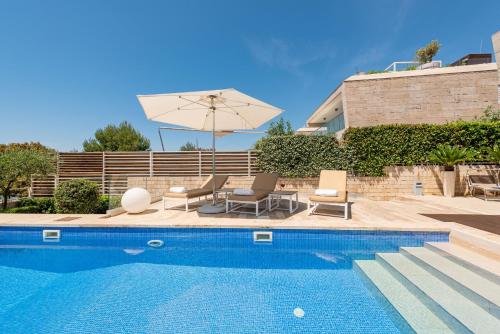 a swimming pool with chairs and an umbrella at Villa Camelia ZadarVillas in Petrcane
