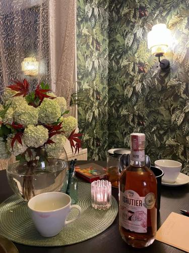 a bottle of alcohol sitting on a table with bowls and flowers at Villa Papírkutya in Veszprém