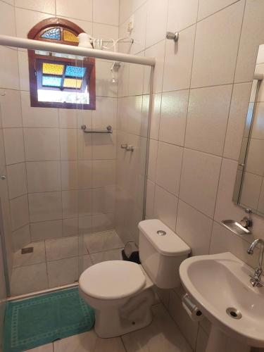 uma casa de banho com um WC, um chuveiro e um lavatório. em Pousada por do soll em Serra do Cipó