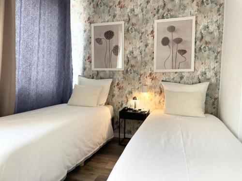 2 camas en una habitación con papel pintado floral en Arina & Julien La Défense-Paris en Suresnes