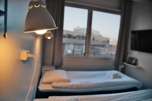 a room with a bed with a lamp and a window at Hotelli Kerava in Kerava