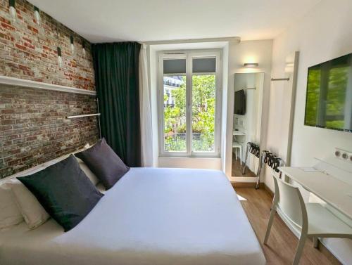 1 dormitorio con cama blanca y pared de ladrillo en Best Western Hotel Le Montparnasse, en París
