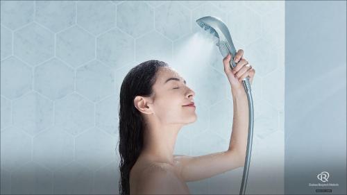 a woman is blow drying her hair with a shower at Daiwa Roynet Hotel Sendai Ichibancho PREMIER in Sendai