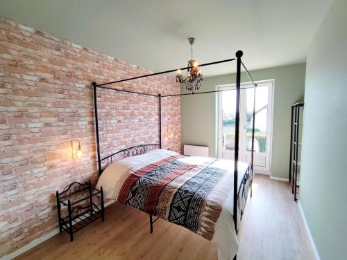 une chambre avec un lit et un mur de briques dans l'établissement Le cocon de Jeannette, à Bergheim