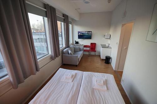 um quarto com uma cama, uma cadeira e uma janela em Hotelli Kerava em Kerava