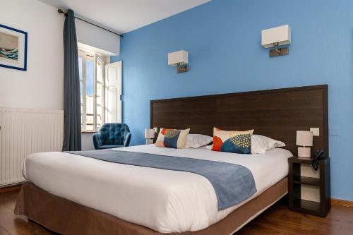 a bedroom with a large bed with a blue wall at Hotel Elizabeth - Intra Muros in Saint Malo
