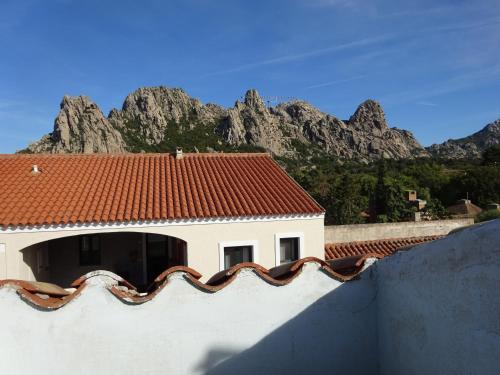 Un edificio con techo rojo con montañas al fondo. en WHITE - San Pantaleo, en San Pantaleo